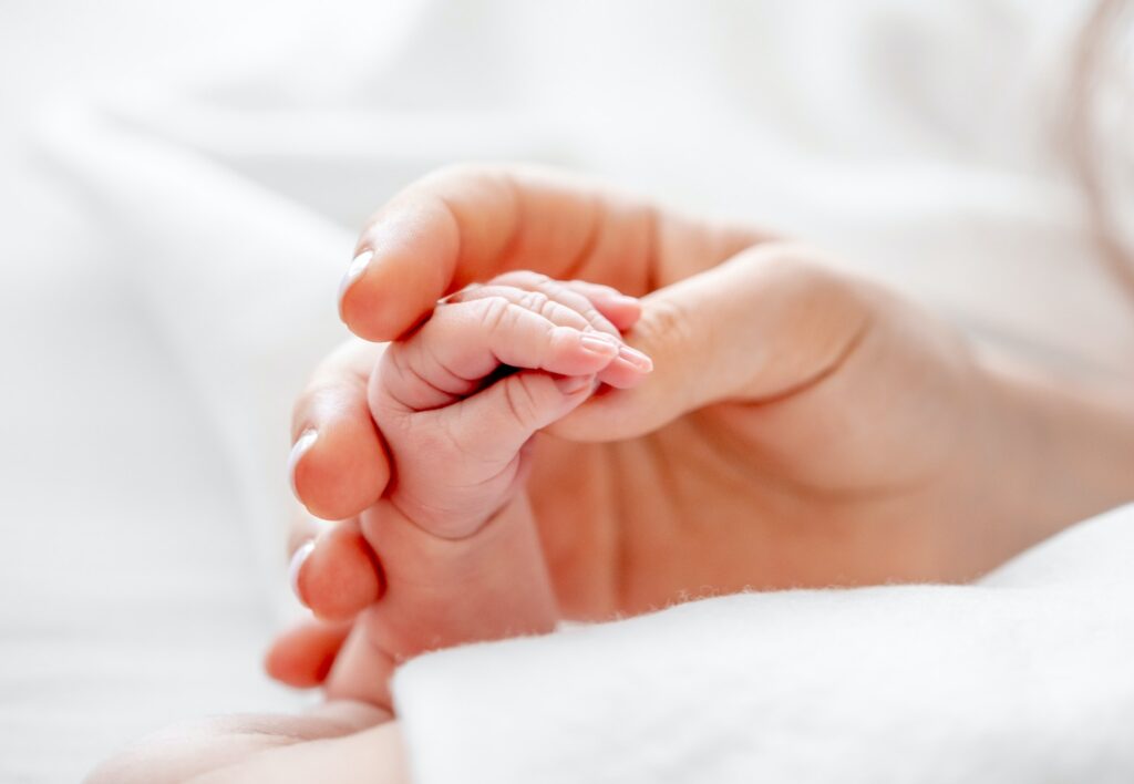 Mother holding newborn baby hand